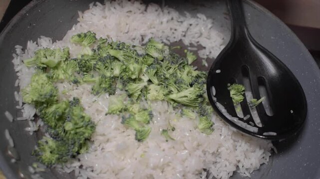 Moviendo arroz con brocoli para preparar comida
