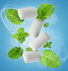 Menthol chewing gum pieces and mint leaves in air against blue background © New Africa
