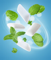 Menthol chewing gum pieces and mint leaves in air against blue background © New Africa