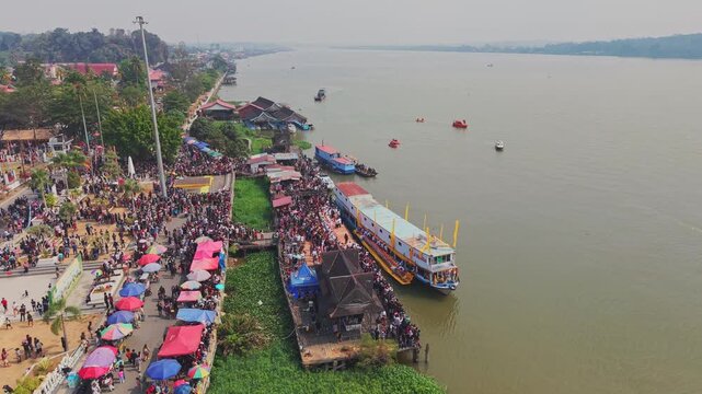 Tenggarong, Indonesia - 27 September 2026: Aerial view of the Ngulur Naga Erau festival with large crowds gathered along the Mahakam riverbank and boats docked.