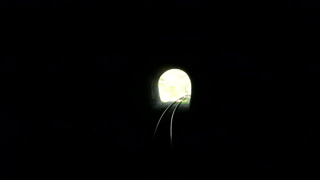 Railway Tracks Lead Through Dark Tunnel Toward Daylight