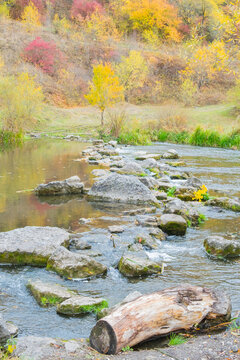 Beautiful river scene with stones and colorful trees in autumn