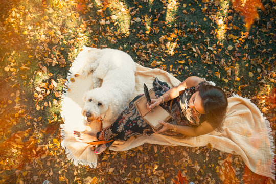 Woman writing a journal, with her dog, outdoors