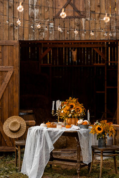 Beautiful fancy fall wedding table decor, countryside style cottage core. Vintage wooden furniture, candlelight, centrepiece with natural sunflowers. Cozy atmosphere, autumn vibes, stylish house decor