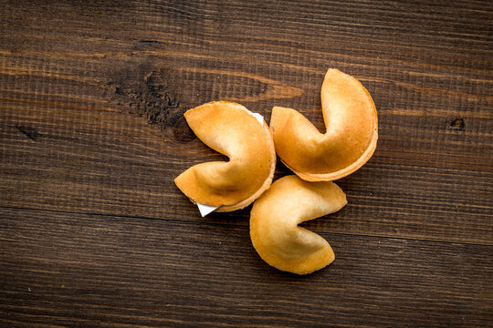 Chinese fortune cookie with prediction on wooden background top view space for text