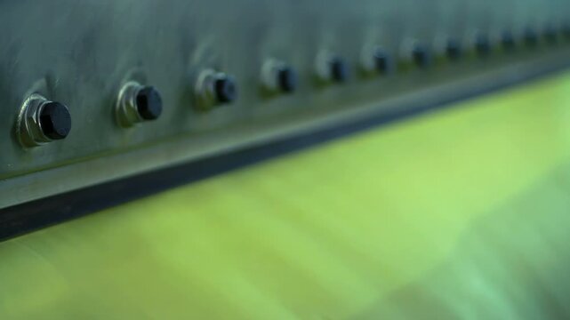 Bolts row steel machine panel closeup. Rack focus dairy plant production line.