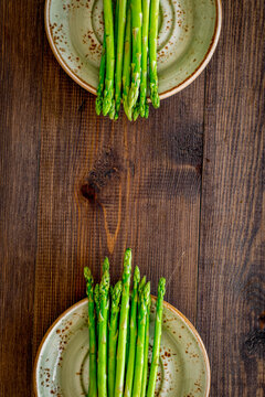 Sprouts of fresh asparagus on dark wooden background top view copyspace
