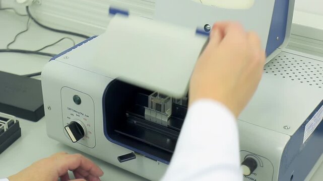 Scientist hands closeup loading cuvettes photometer. Lab technician closing lid.