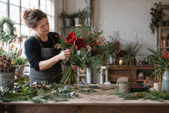 Fiorista prepara un bouquet invernale con fiori rossi