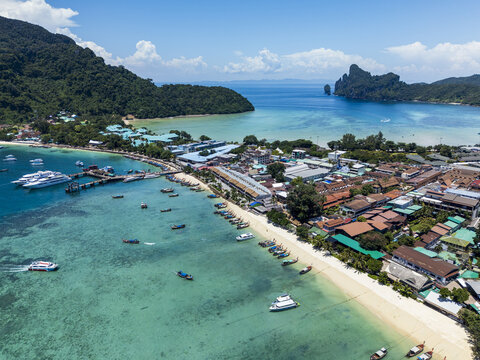 Aerial view of Phi Phi Islands featuring turquoise waters, sandy beaches, long-tail boats, and coastal buildings in Mueang Krabi District, Krabi, Thailand.