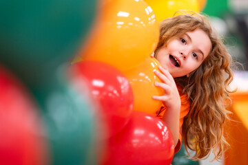 Fototapeta na wymiar Festive balloons frame a smiling child. Festive decoration fills the bright background. Happy kid enjoys the festive event. Colorful balloons strengthen the festive portrait.