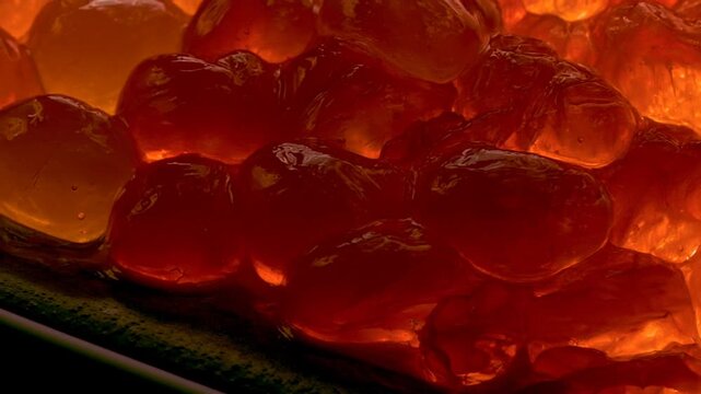 Glowing translucent grapefruit pulp in extreme closeup, backlit juice vesicles in deep orange and red, evoking zesty citrus aroma and vitality