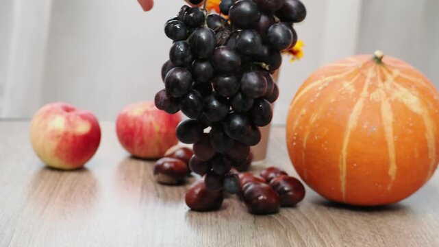 Autumn Thanksgiving arrangement, still-life background. Harvested pumpkins, a beautiful bouquet of yellow and orange flowers, fruits and vegetables, autumn leaves, and red berries on a wooden table. A