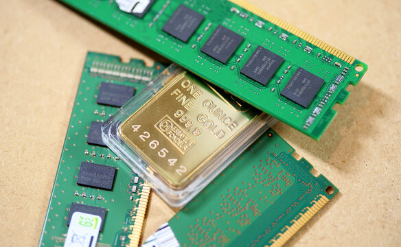 One ounce fine gold bar 999.9 in blister pack on three green RAM memory modules with Hynix chips, memory price surge and AI shortage concept, macro closeup on brown cardboard