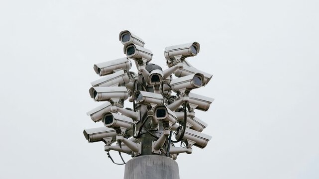 Dense cluster of security cameras mounted on a single pole against a blank white sky, pointing in every direction, concept of mass surveillance and privacy