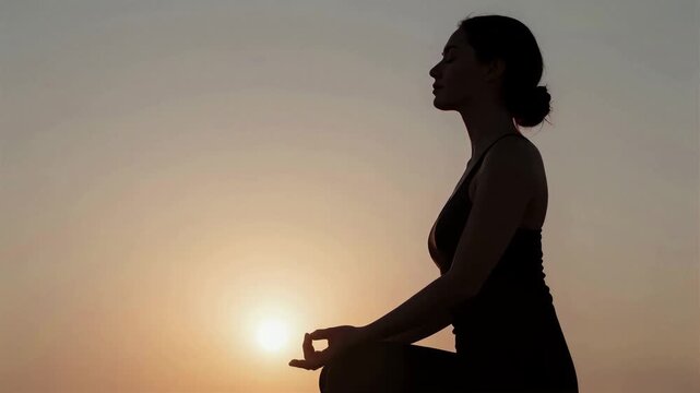 Silhouette profile of a person meditating in a zazen pose against a warm golden hour sunset light, 4K, Seamless loop, Copy space on the left, Side view