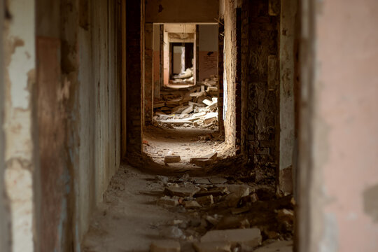 Abandoned building corridor with peeling plaster and construction debris. Urban exploration of a decaying interior. Building disrepair and structural neglect. Ruin, decay and passage concept
