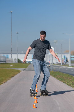 A Caucasian man rollerblades around the slalom course.