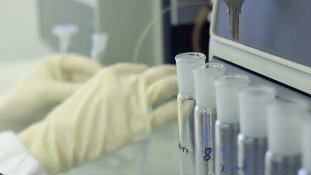 Test tubes row laboratory close up. Gloved hands volumetric flask lab analyzer.