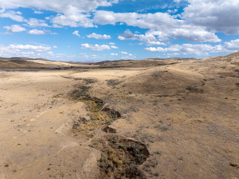 Desolate desert landscape with cracked earth and distant hills under cloudy sky