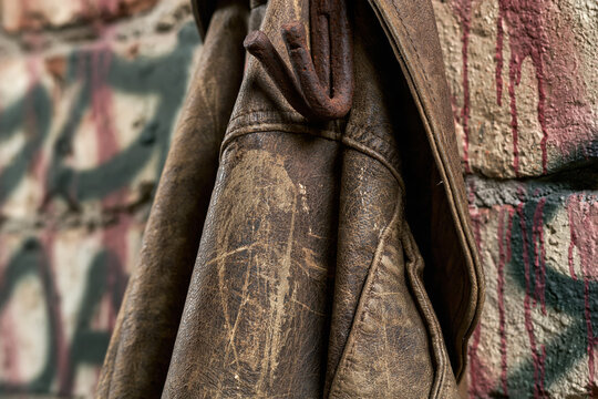 Vintage leather jacket hanging on a rusted hook in a worn area