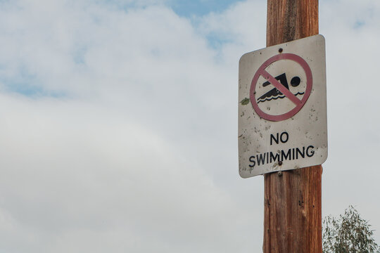 no swimming sign against overcast sky