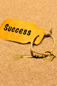 Old vintage key in sand with a card label with the word success. Phrase 'key to success' concept