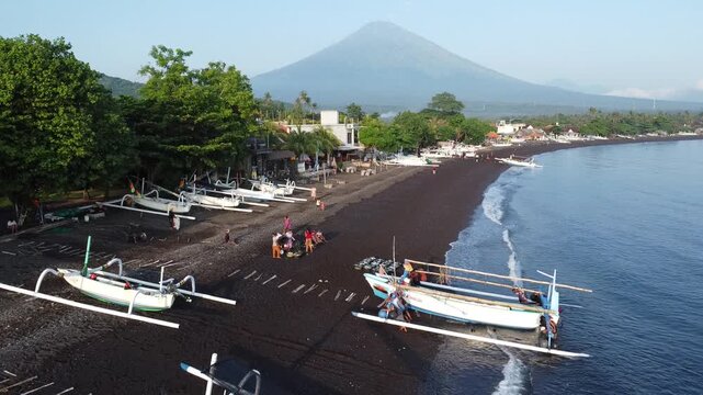 Fishermen return in the morning with their outrigger boats to the black beach of Amed, with Mount Agung in the background, Amed Bali, Indonesia