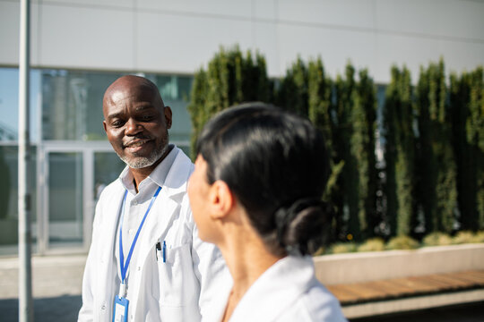 Smiling doctor chatting with colleague outside hospital