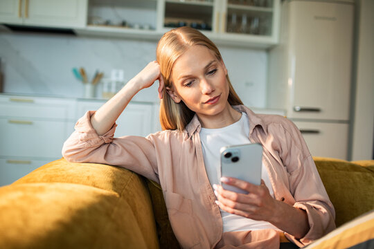 Woman relaxing on sofa at home with smartphone