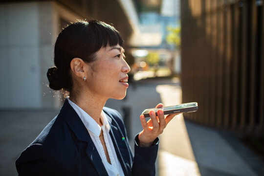 Businesswoman using voice input on smartphone outdoors
