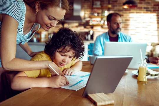 Parent helping child with homework at kitchen table