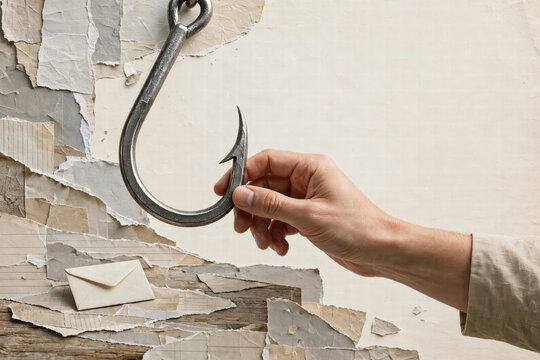 Fishing hook hand removing envelope from torn wall, concept of bait, temptation, trap, and hidden message in weathered paper surface
