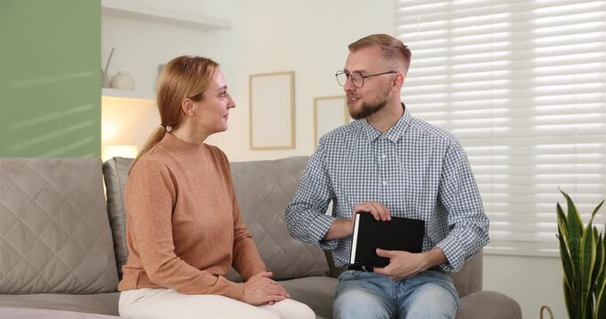 Pastor conducting Bible study with woman on sofa indoors