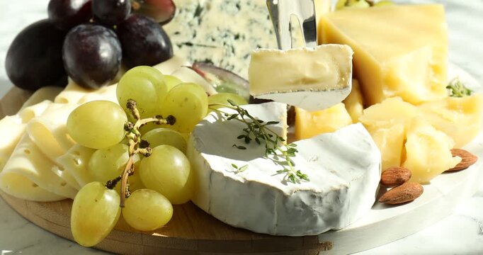 Taking piece of cheese, fresh grapes, nuts and thyme at table, closeup