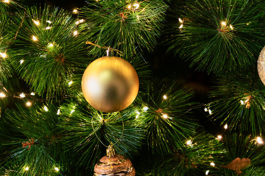 Golden Christmas Bauble Hanging on an Illuminated Pine Tree