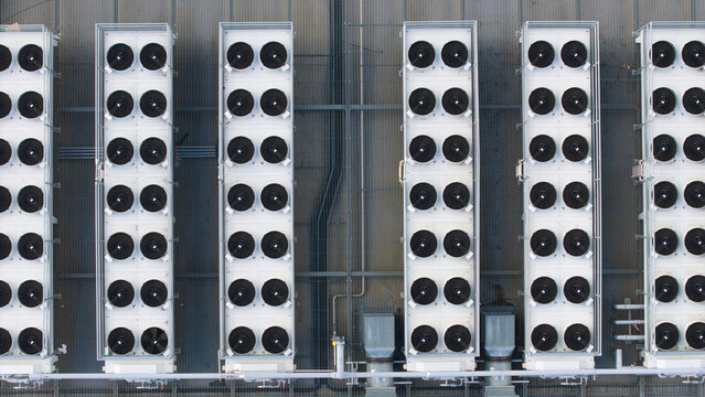 Aerial view of rows of industrial HVAC ventilation and cooling fans installed on a flat rooftop in Peterborough, England, United Kingdom.