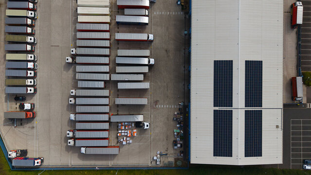Aerial view of industrial logistics warehouses with rows of parked HGVs and trailers in the yard in Bury St Edmunds, England, United Kingdom.