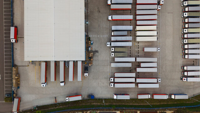 Aerial view of industrial logistics warehouses with rows of parked HGVs and semi-trailers in a distribution center in Bury St Edmunds, England, United Kingdom.