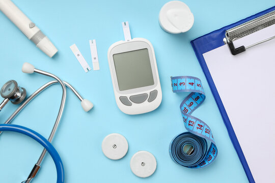 Glucose meter and strips with medical tools on blue