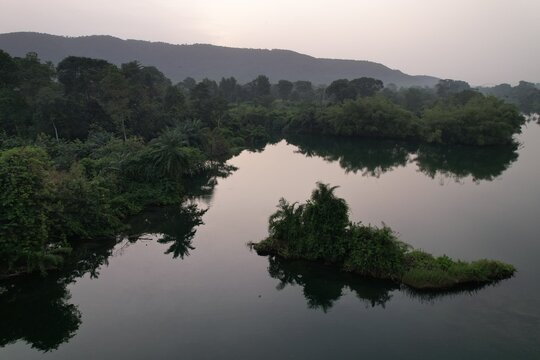 Aerial view of the Volta River with lush green vegetation, small islands, and dense forests under a soft sky in Akosombo, Eastern Region, Ghana.
