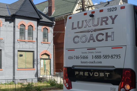 rear view of a Prevost luxury-coach service parked on Dundas St W with view of historic house, Toronto