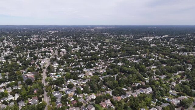 A drone glides over leafy Babylon neighborhoods on Long Island in New York with detached houses and residential streets stretching to the horizon.