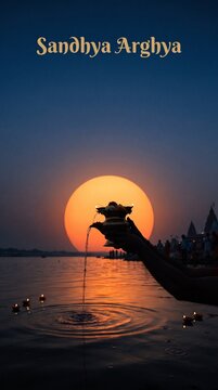 Hands holding brass pot pouring water into river during sunrise for ritual sandhya arghya.