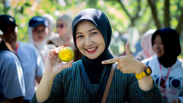 Asian woman holding Rose sapote (ross sapote, zapote amarillo, Pouteria sp, canistel, alkesa, sawo mentega) fruit.