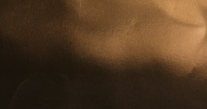 Brushed bronze metal surface texture with scratches and light