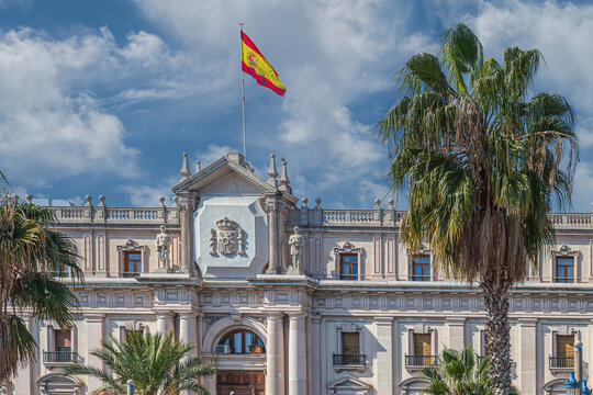The neoclassical fa&ccedil;ade of the Captaincy General of Barcelona on Passeig de Colom, featuring statues, coat of arms, stone balconies, and the Spanish flag near the port and Columbus Monument.