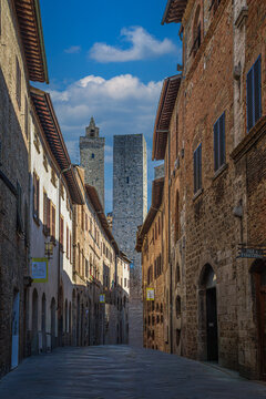 San Gimignano, Italy - May 23, 2026: Narrow cobblestone street lined with historic buildings and medieval towers in the UNESCO-listed Tuscan town of San Gimignano.