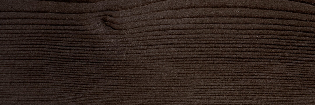Close-up of dark brown textured wood with parallel grooves.