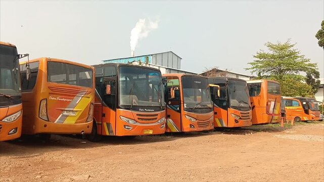 Fleet of orange shuttle buses parked near factory